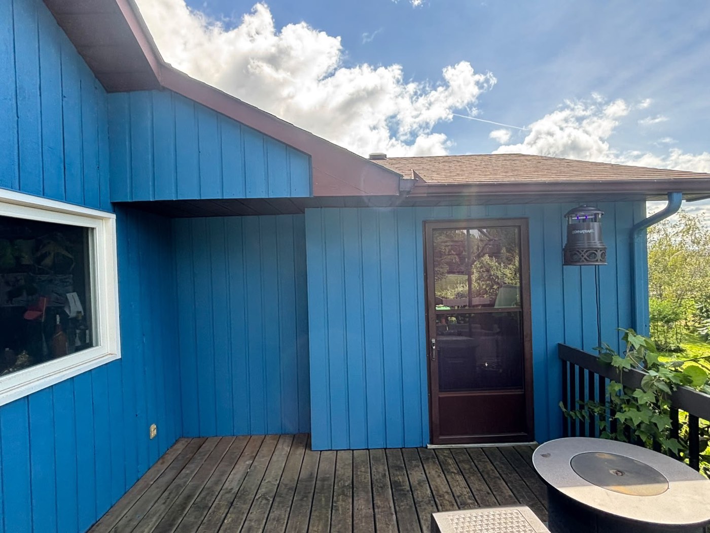 Freshly painted blue exterior siding with back deck and door