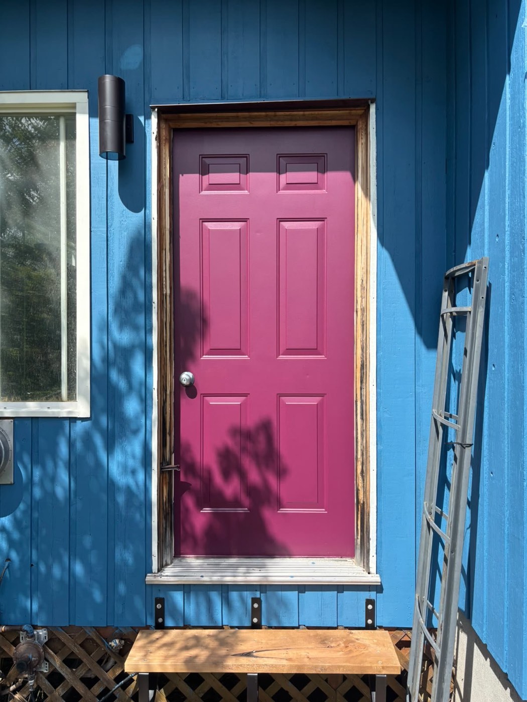 Freshly painted magenta front door with blue siding