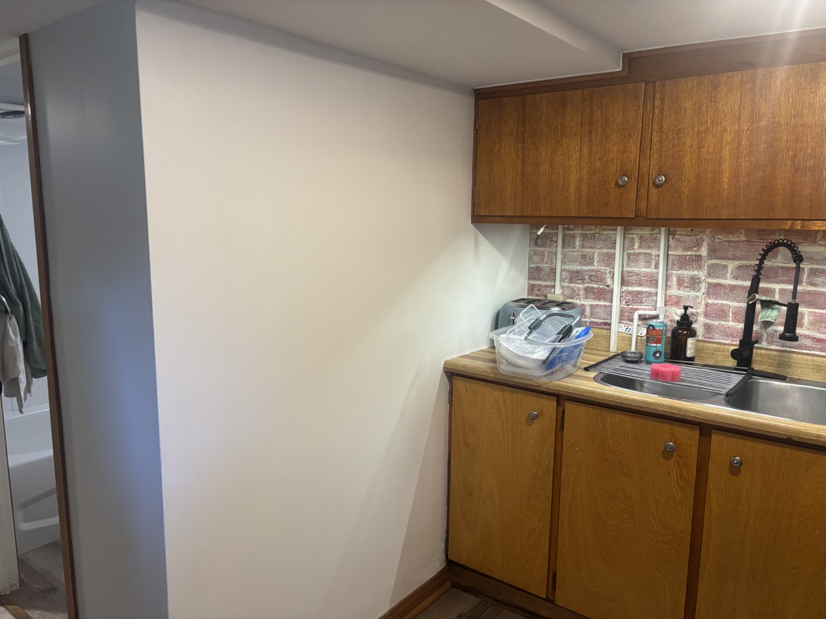 Freshly painted kitchen with grey accent wall and wood cabinets