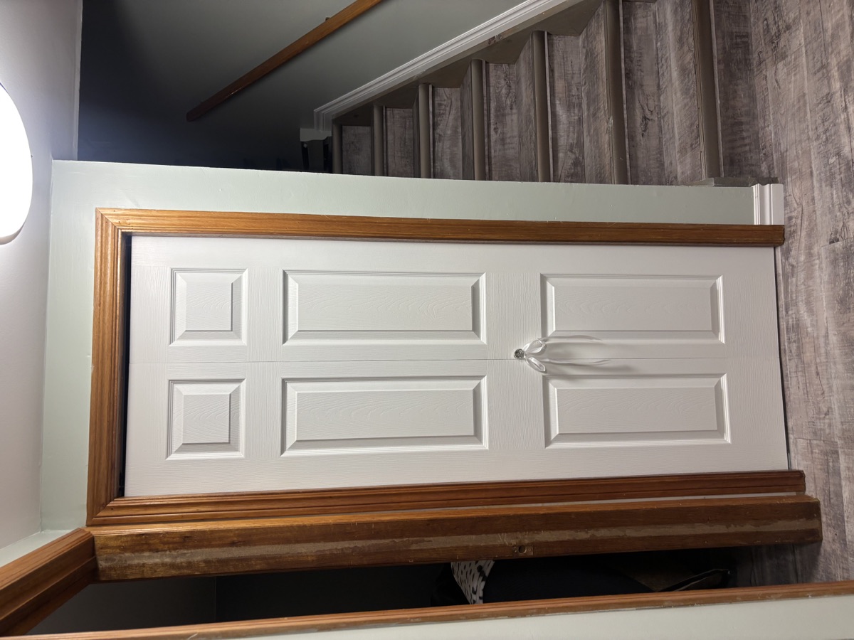 Freshly painted sage green stairwell with white door